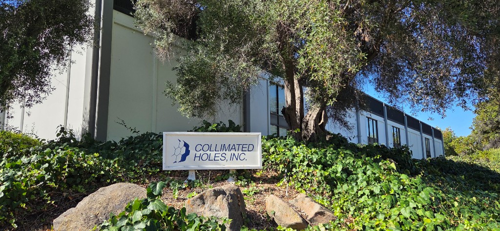 Exterior view of the Collimated Holes, Inc. building and company sign in 1974, featuring modern architecture and lush landscaping